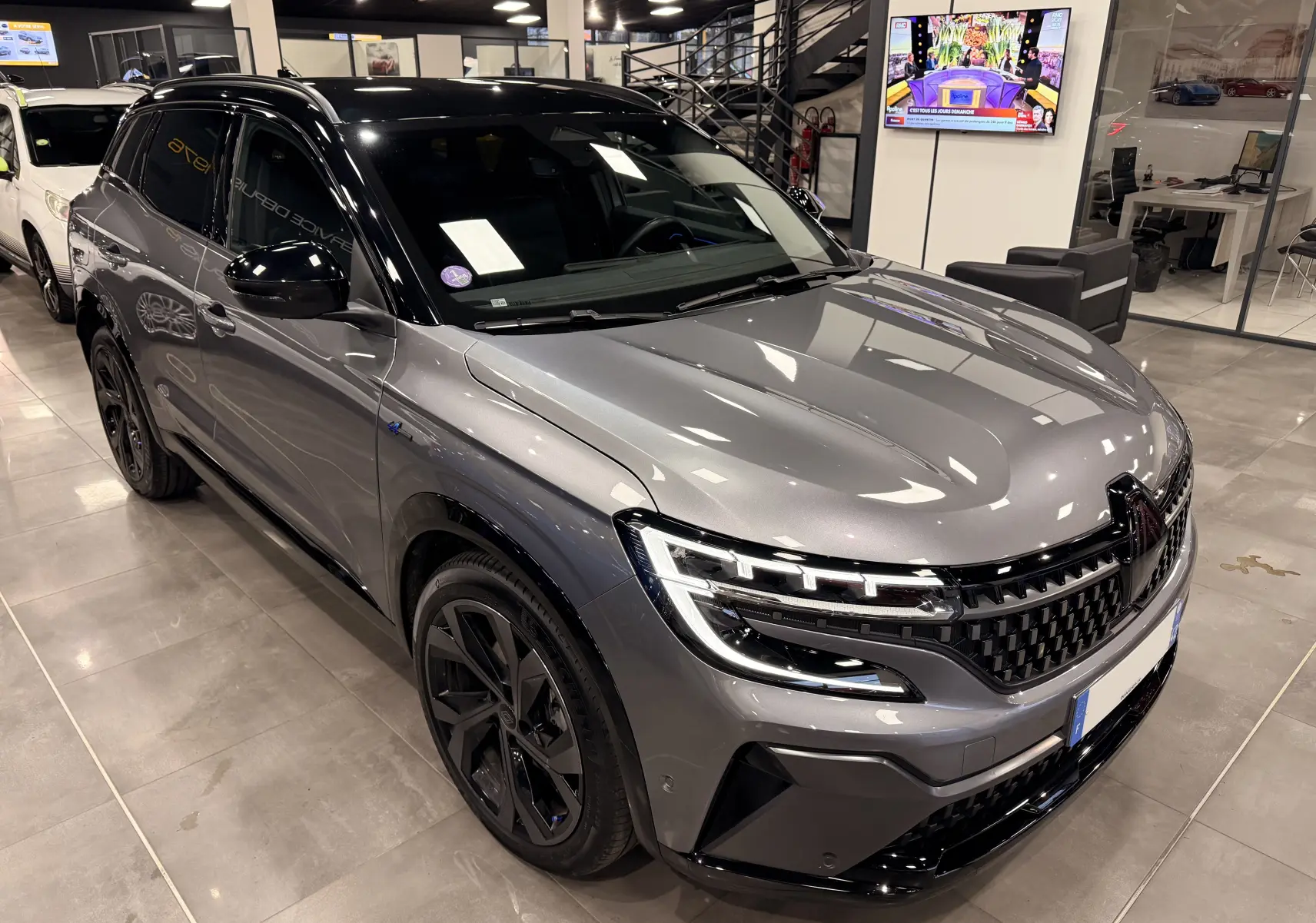 Renault Austral E-Tech gris schist avec toit noir, vue 3/4 avant droit mettant en valeur ses phares LED et jantes noires.