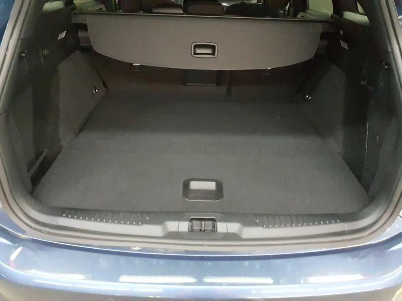 Vue du coffre ouvert d'une Ford Focus SW 2023 Bleu Azur, montrant l'espace de chargement vide et la finition intérieure noire.
