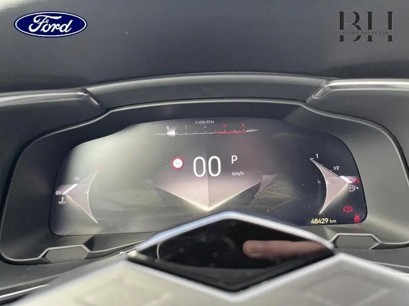 Tableau de bord numérique d'un DS7 gris laqué, affichage vitesse et compte-tours en vue frontale rapprochée.