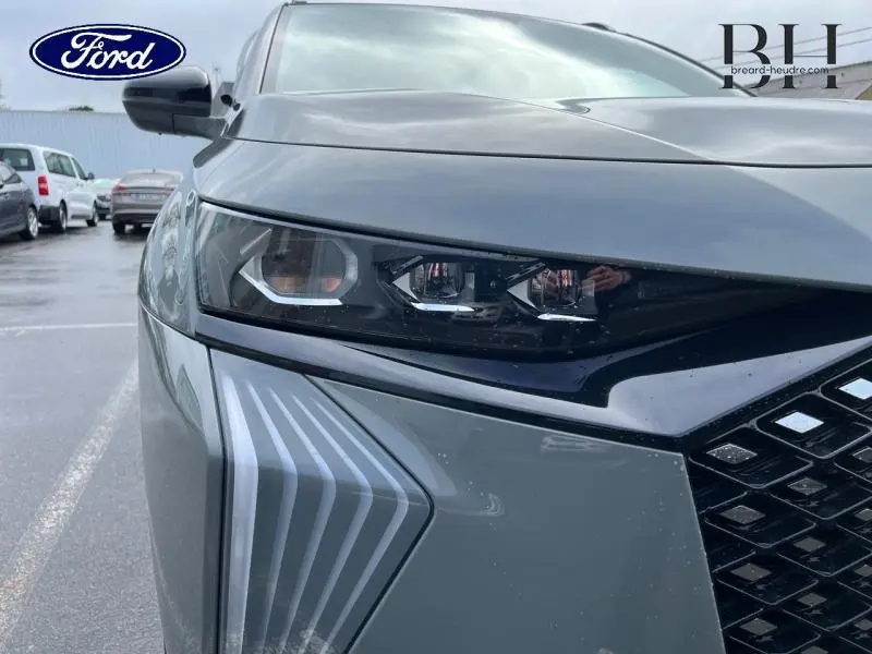 Gros plan sur le phare avant droit gris laqué du DS7 2023 avec détails lumineux et calandre noire brillante.