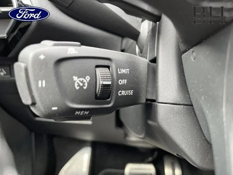 Gros plan sur la commande de régulateur de vitesse noire dans l'habitacle du DS7 Gris Laqué, côté gauche du volant.