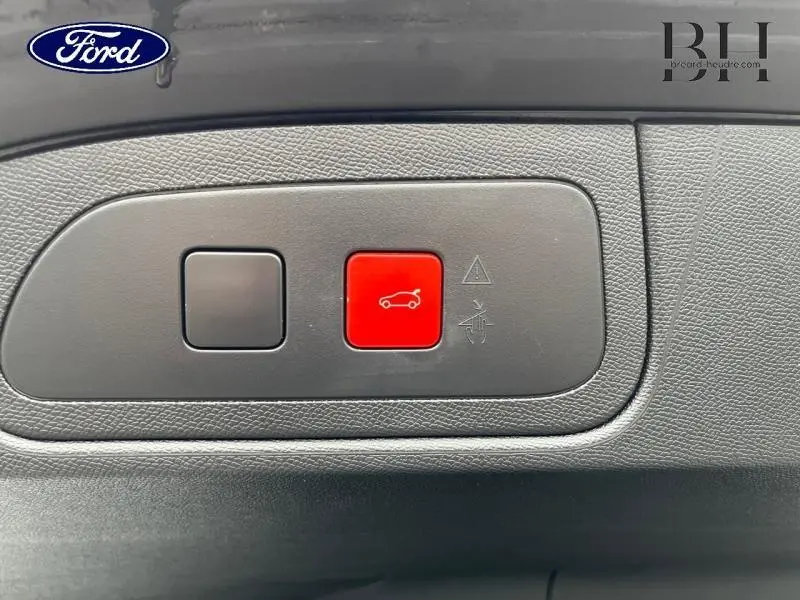 Bouton rouge d'ouverture électrique du coffre sur panneau intérieur gris d'un DS7 Gris Laqué, vue rapprochée.