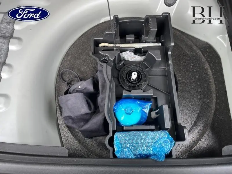 Vue plongeante sur le coffre d’un DS7 gris laqué, montrant le rangement d’outils et accessoires emballés en bleu.