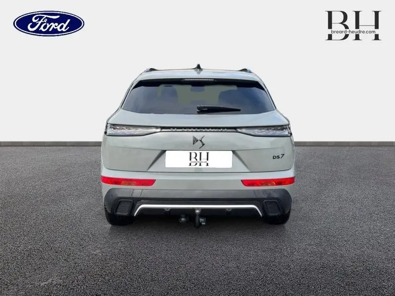 Vue arrière d'un DS7 gris laqué 2023 avec feux LED fins et attelage visible sur un sol goudronné.
