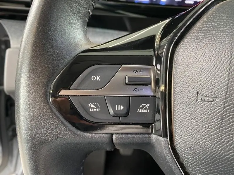 Gros plan sur les commandes de régulateur de vitesse au volant cuir noir de la Peugeot 308 gris Artense 2022.