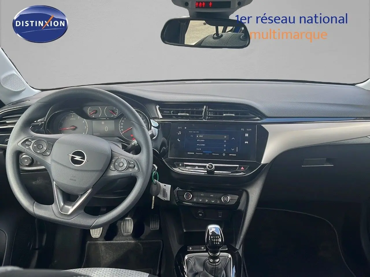 Vue intérieure avant de l'Opel Corsa 2025 avec volant multifonction, tableau de bord moderne et levier de vitesse manuel.