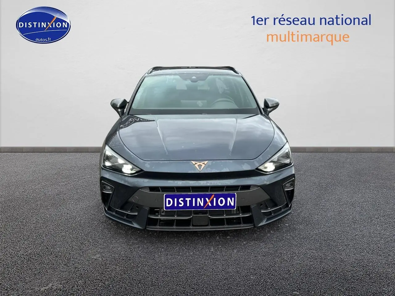 Vue avant d'une CUPRA Leon ST 1.5 etsi hybrid gris magnétique avec phares LED allumés et logo cuivré visible.