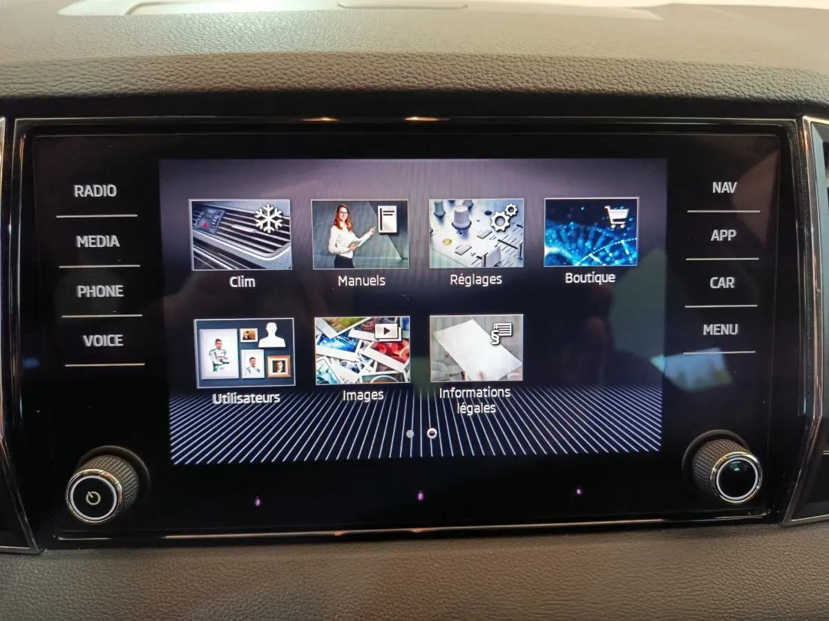 Écran tactile central du tableau de bord du Skoda Karoq blanc, affichant le menu multimédia et réglages.