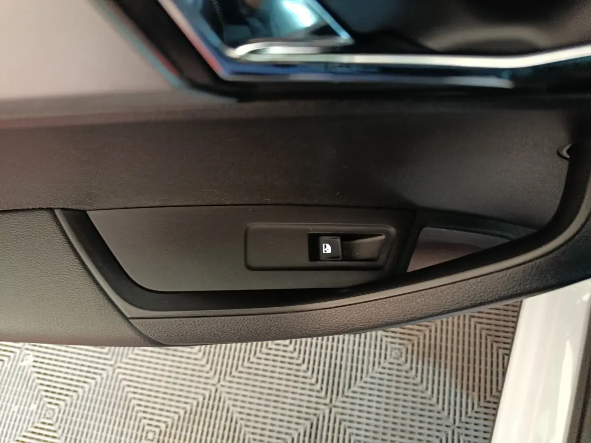 Détail du bouton d'ouverture de trappe à carburant sur la porte côté gauche d'un Skoda Karoq blanc 2024.