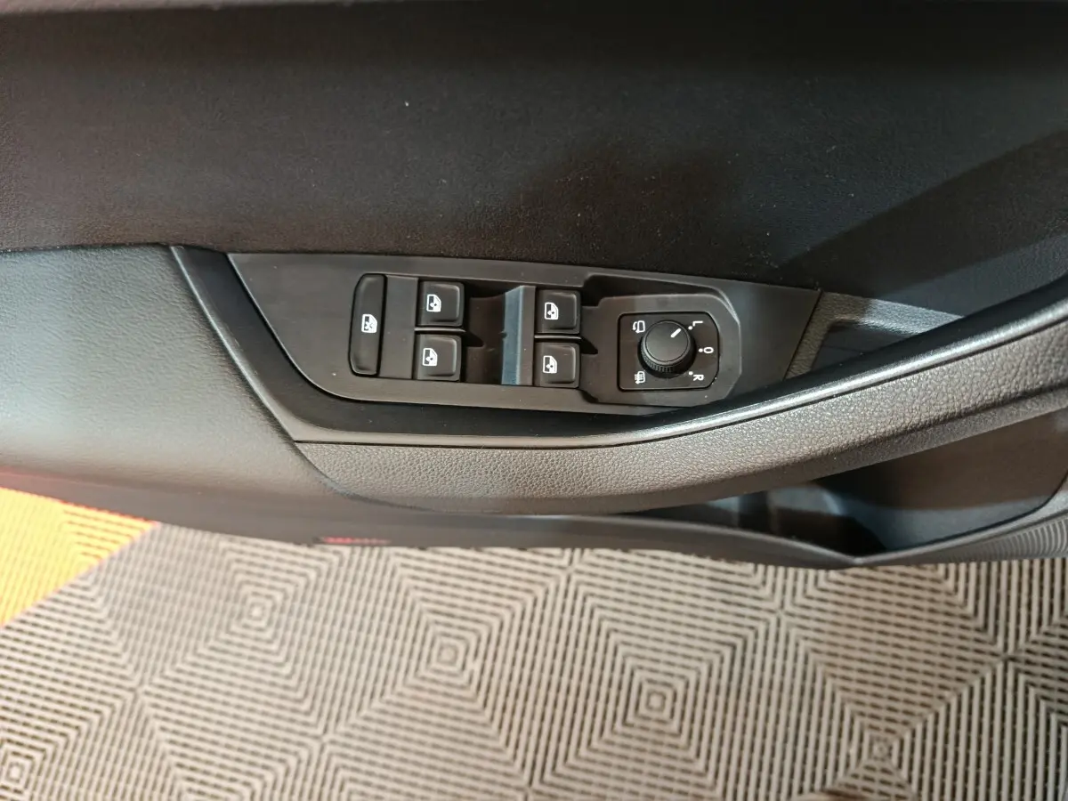 Commandes des vitres et rétroviseurs côté conducteur du SKODA KAROQ blanc 2024, vue rapprochée intérieure.