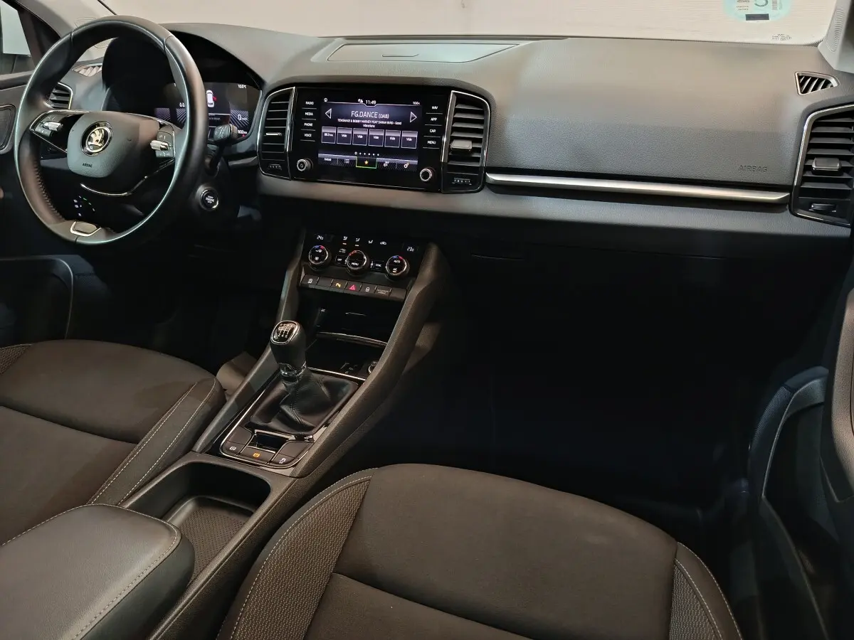Intérieur noir du Skoda Karoq 2.0 TDI 2024, vue côté conducteur sur tableau de bord et console centrale avec boîte manuelle.