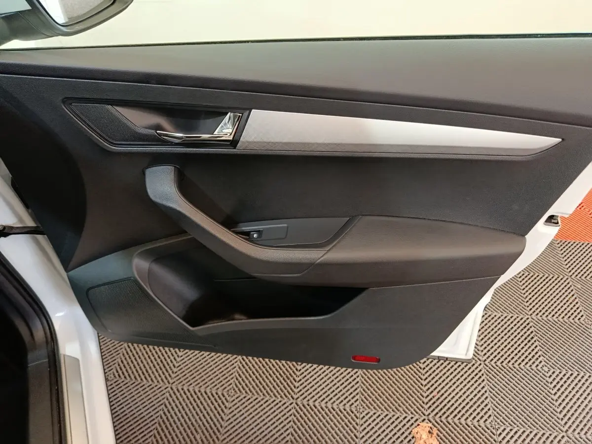 Intérieur côté gauche de la porte avant d'un Skoda Karoq blanc, avec garniture noire et insert argenté.