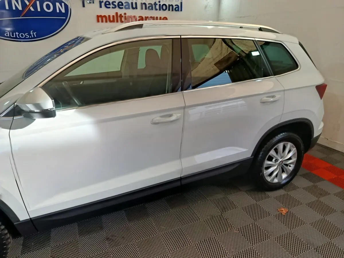 Vue latérale côté gauche d'un Skoda Karoq blanc 2024 avec jantes alliage et rétroviseurs électriques.