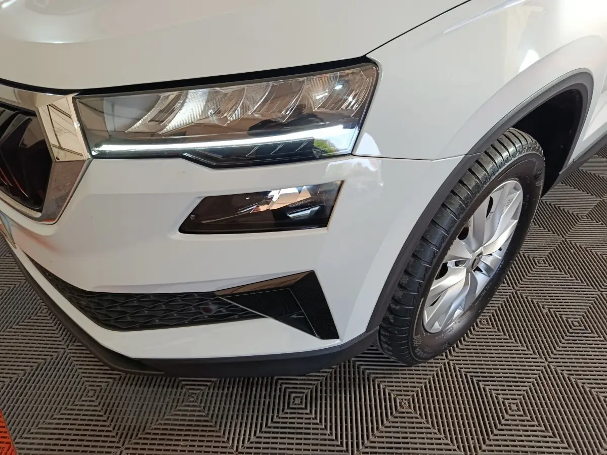 Gros plan sur l'avant droit blanc du Skoda Karoq 2.0 TDI avec phares LED et jante alliage visible.