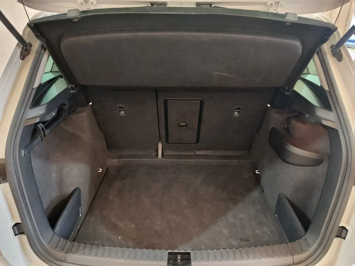Coffre ouvert vu de l'arrière d'un SKODA KAROQ blanc, intérieur de coffre spacieux et revêtement noir.