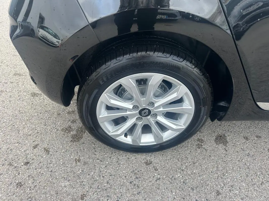 Gros plan sur la roue avant droite d'une Renault Clio noire 2025, mettant en valeur la jante argentée au design moderne.