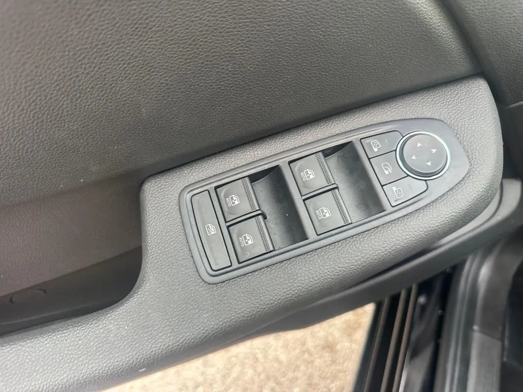 Gros plan sur les commandes des vitres électriques et réglages des rétroviseurs côté conducteur de la Renault Clio noire 2025.