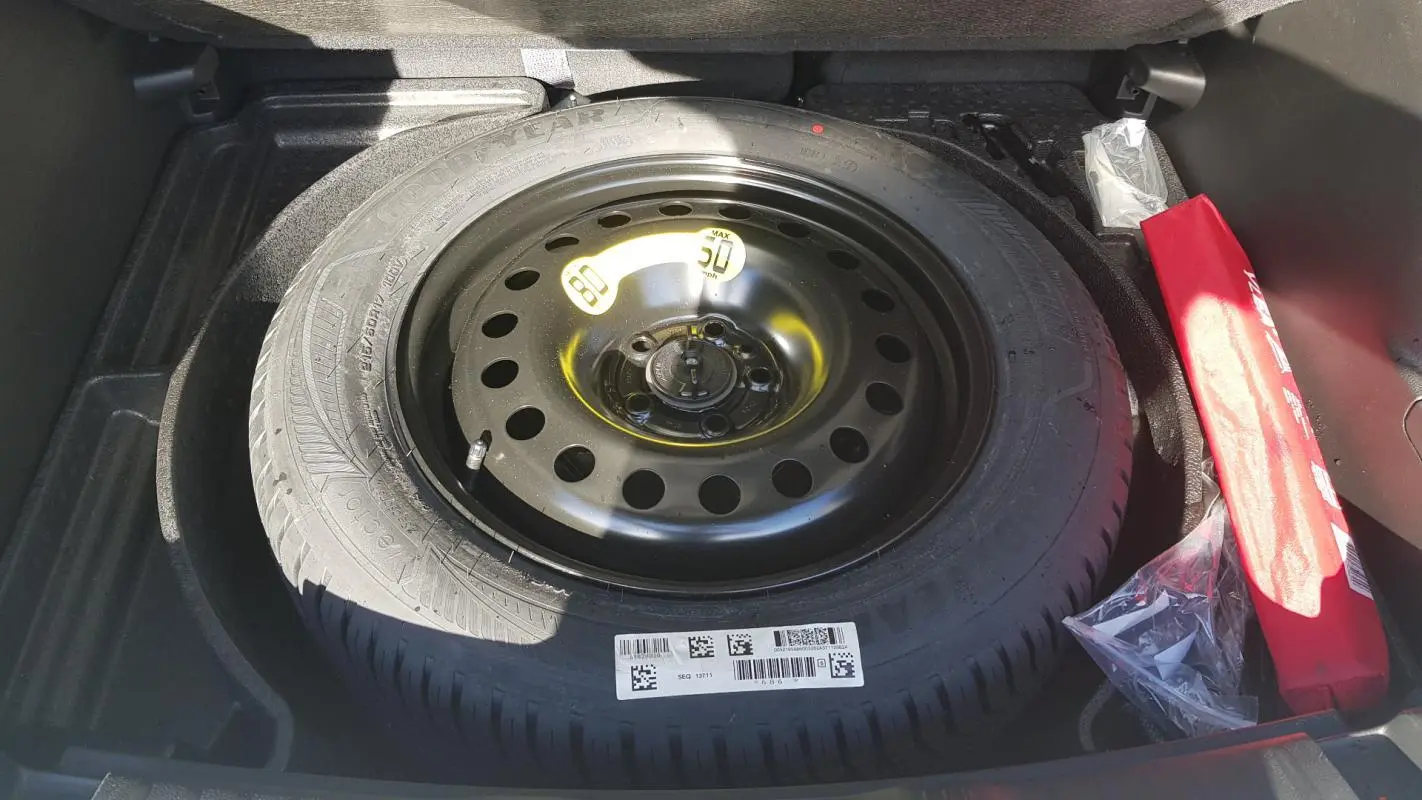 Gros plan sur la roue de secours noire dans le coffre du Jeep Compass blanc 2024 e-Hybrid Altitude.