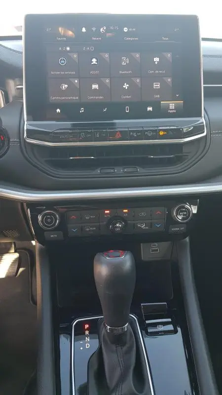 Vue rapprochée de la console centrale du Jeep Compass 2024 avec écran tactile, commandes climatisation et levier de boîte automatique.