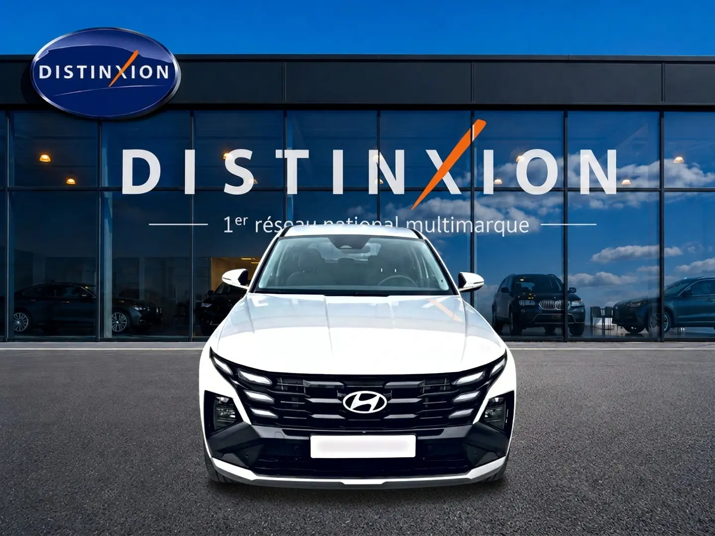 Vue de face du Hyundai Tucson blanc 2026 avec calandre noire distinctive devant une vitrine Distinxion.