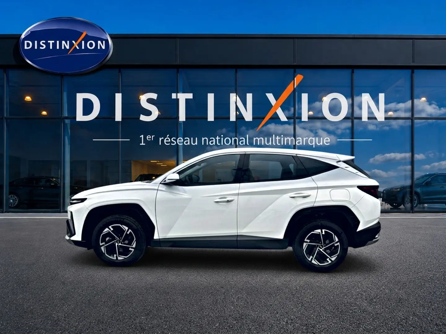 Hyundai Tucson blanc en profil droit devant une vitrine avec logo Distinxion, jantes alliage noires et blanches.