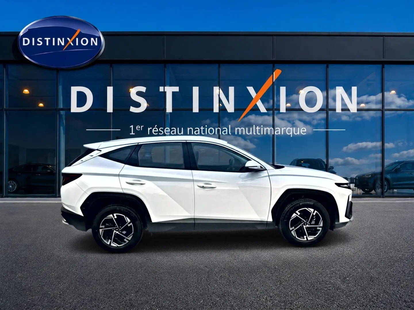 Profil droit du Hyundai Tucson blanc 2026 avec jantes alliage 17 pouces, devant une vitrine Distinxion.