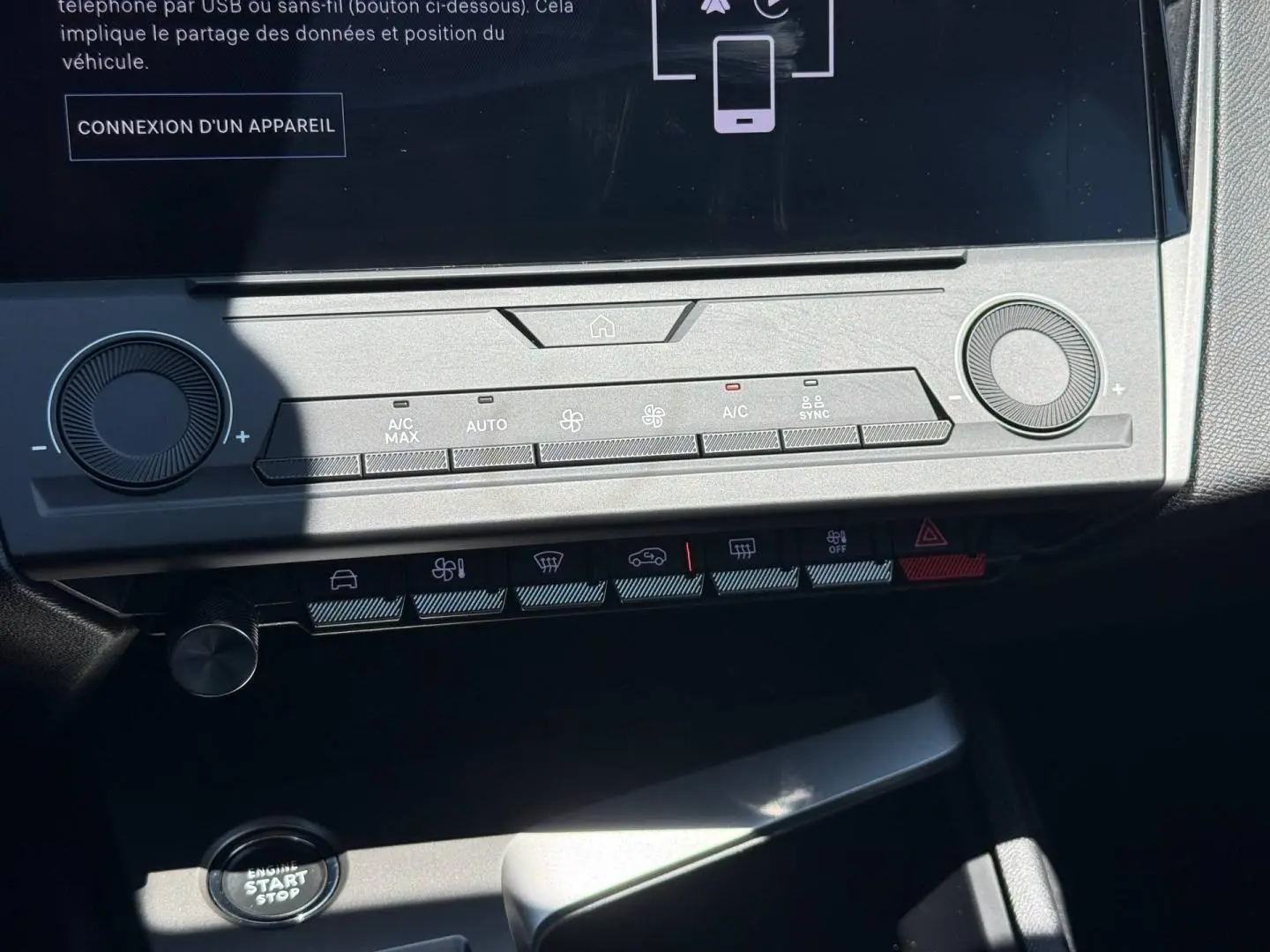 Vue rapprochée de la console centrale de la Peugeot e-308 gris Artense, montrant l'écran tactile et les commandes climatisation.