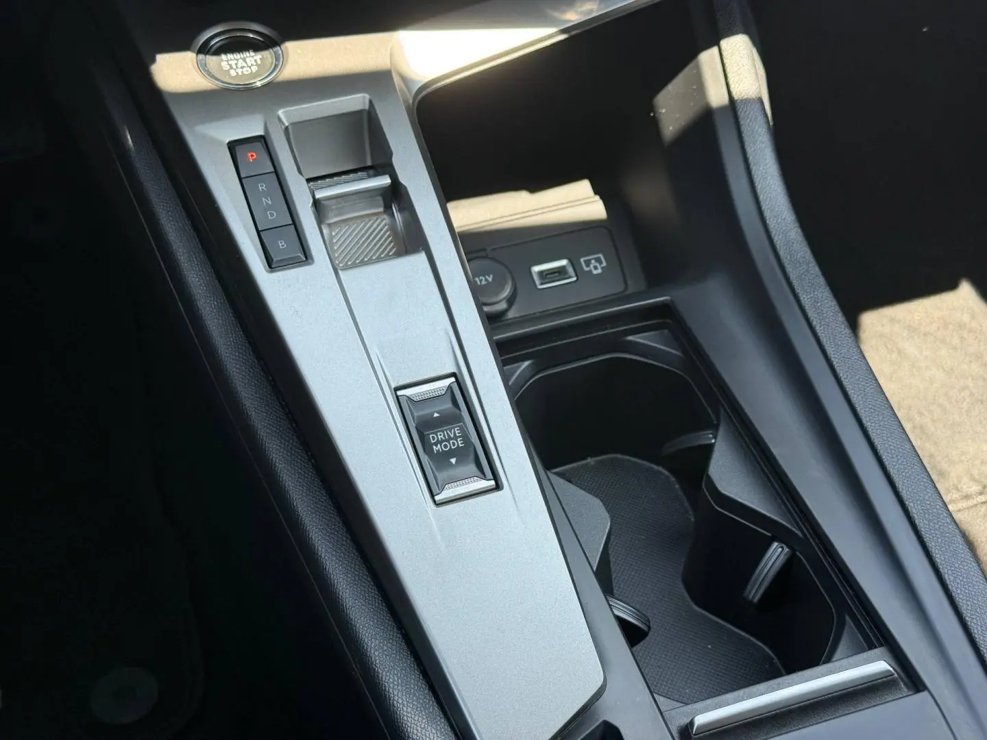 Gros plan sur la console centrale de la Peugeot e-308 gris Artense, avec levier de vitesses automatique et bouton Drive Mode.