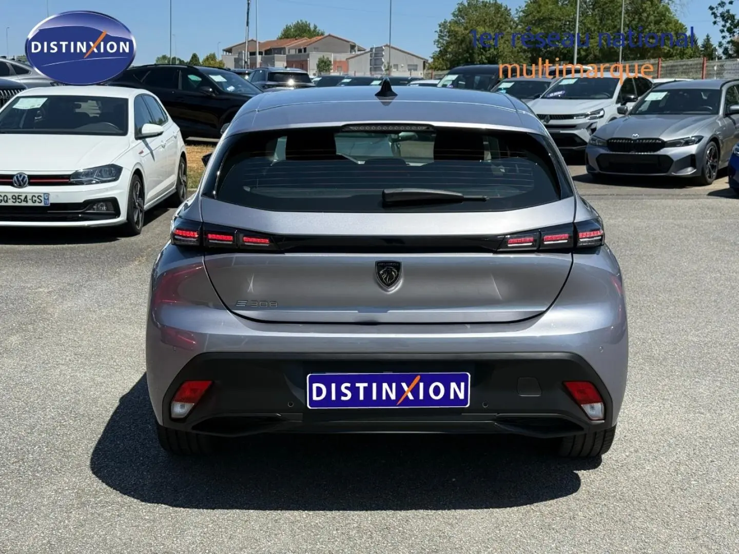 Vue arrière d'une Peugeot e-308 gris Artense 2025 avec feux LED et logo lion central sur parking.