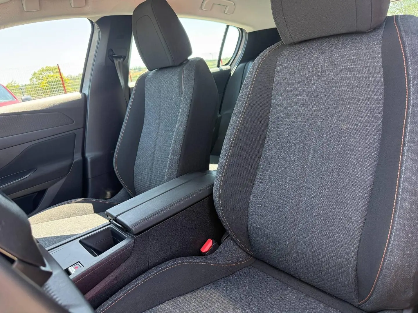Vue intérieure rapprochée des sièges avant gris tissu avec accoudoir central de la Peugeot 308 e-308 2025.