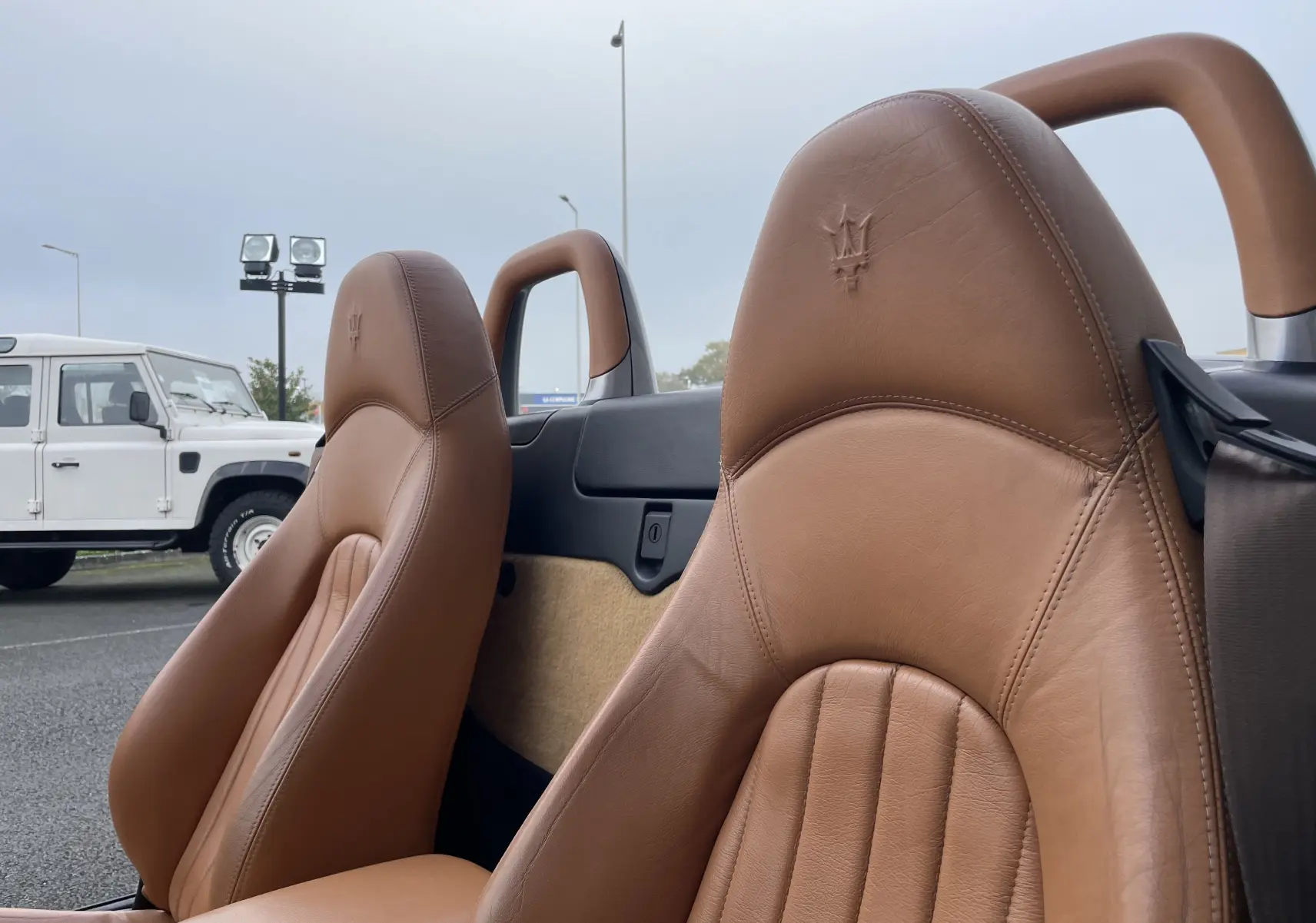 Gros plan sur les sièges en cuir marron avec logo Maserati embossé, intérieur du Spyder gris Nuvolari cabriolet 2002.