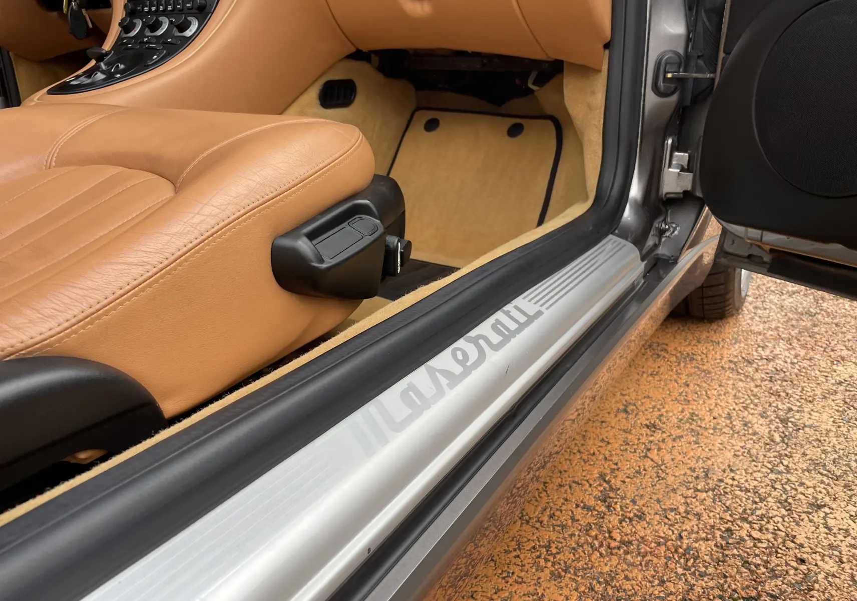 Vue rapprochée de l'entrée côté gauche d'une Maserati Spyder gris Nuvolari avec intérieur cuir beige et seuil marqué Maserati.