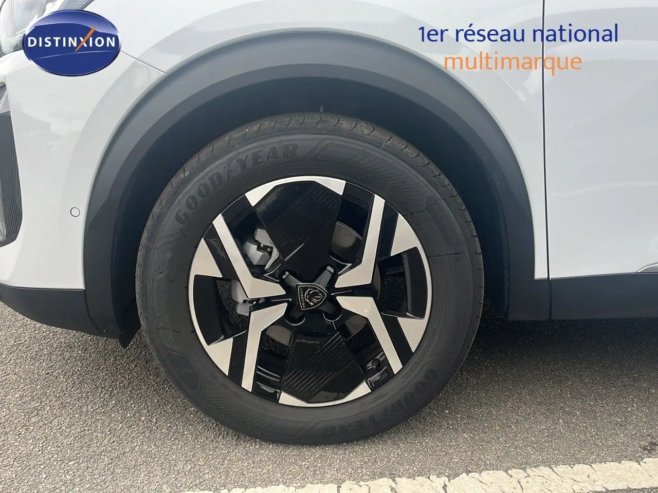 Gros plan sur la roue avant droite d'un Peugeot 2008 blanc Okenite Metal avec jante noire et argentée au design moderne.