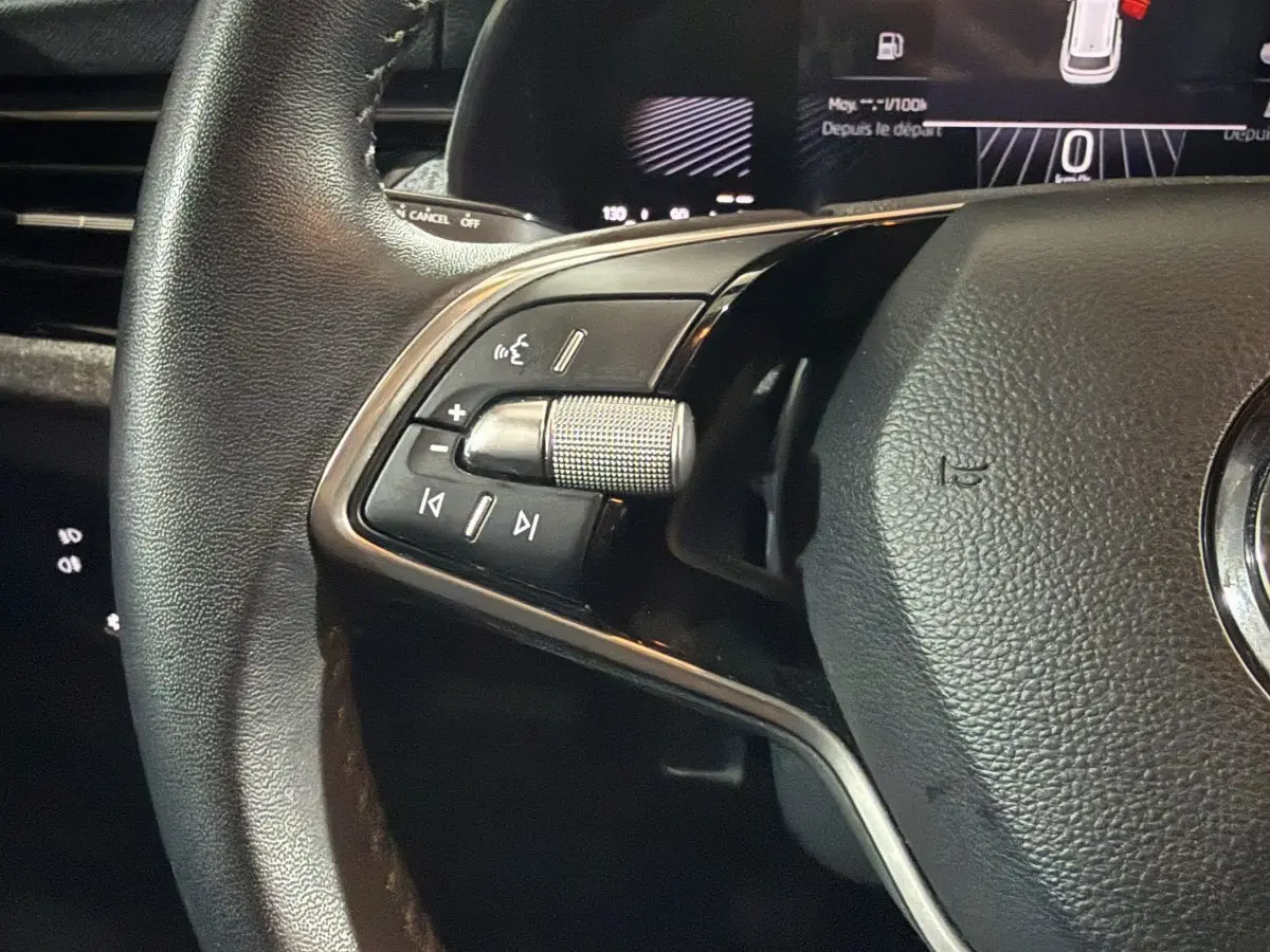 Gros plan sur la partie gauche du volant cuir du Skoda Kamiq rouge 2024 avec commandes multimédia intégrées.