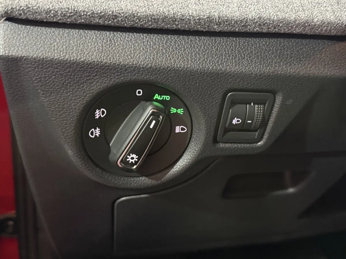Gros plan sur le bouton de commande des phares avec réglage automatique sur Skoda Kamiq rouge 2024.