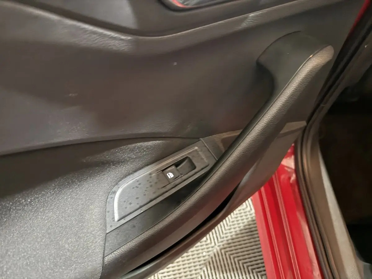 Poignée de porte intérieure noire côté conducteur sur SKODA KAMIQ rouge, avec bouton de verrouillage des vitres.