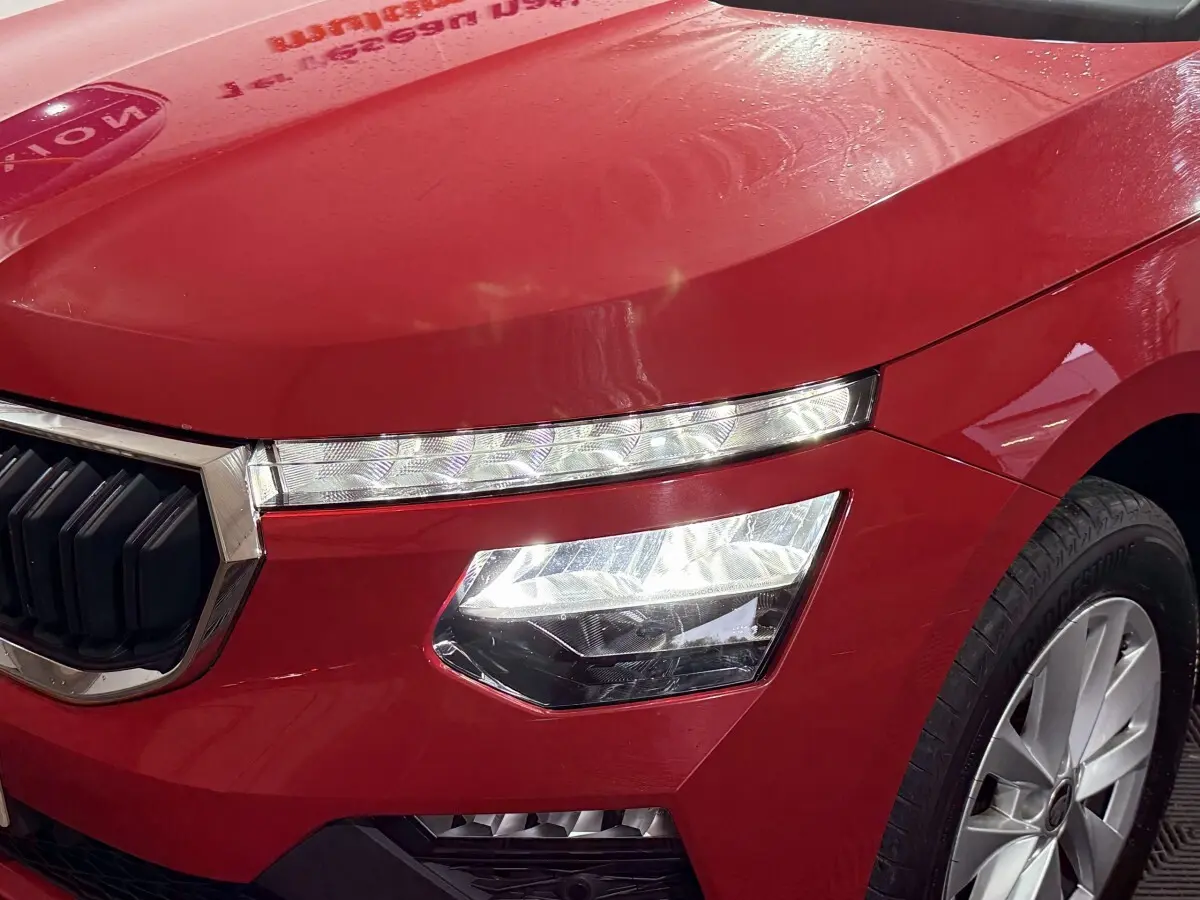 Gros plan sur l'avant droit rouge d'un Skoda Kamiq 2024, mettant en valeur ses phares LED et la calandre chromée.