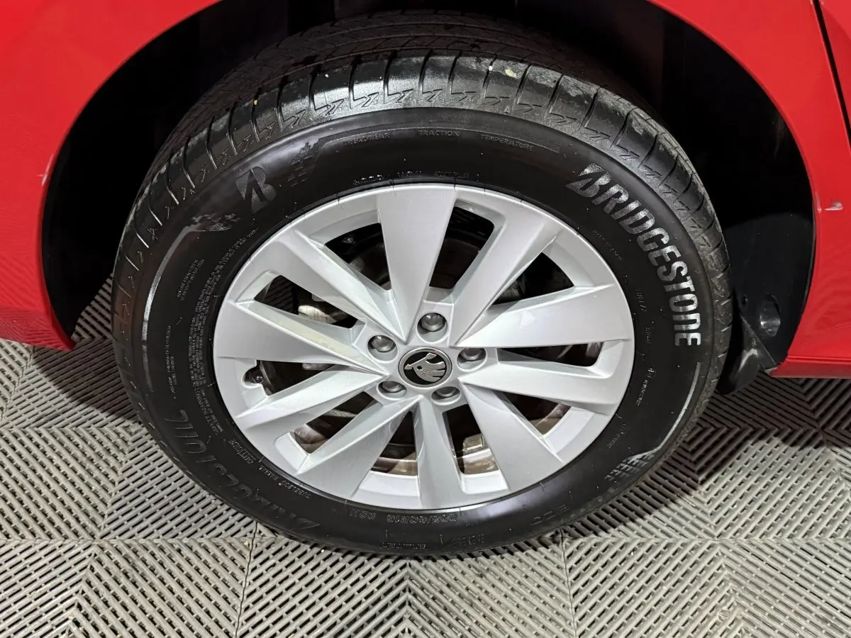 Gros plan sur la roue avant droite d'une SKODA KAMIQ rouge 2024 avec jante argentée et pneu Bridgestone.