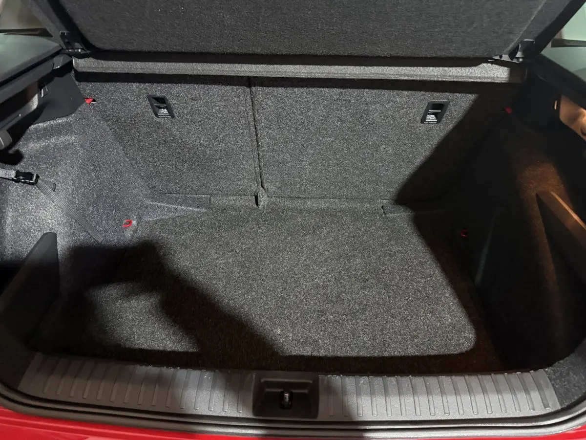 Coffre ouvert vu de l'arrière d'un Skoda Kamiq rouge 2024, espace de chargement tapissé gris.