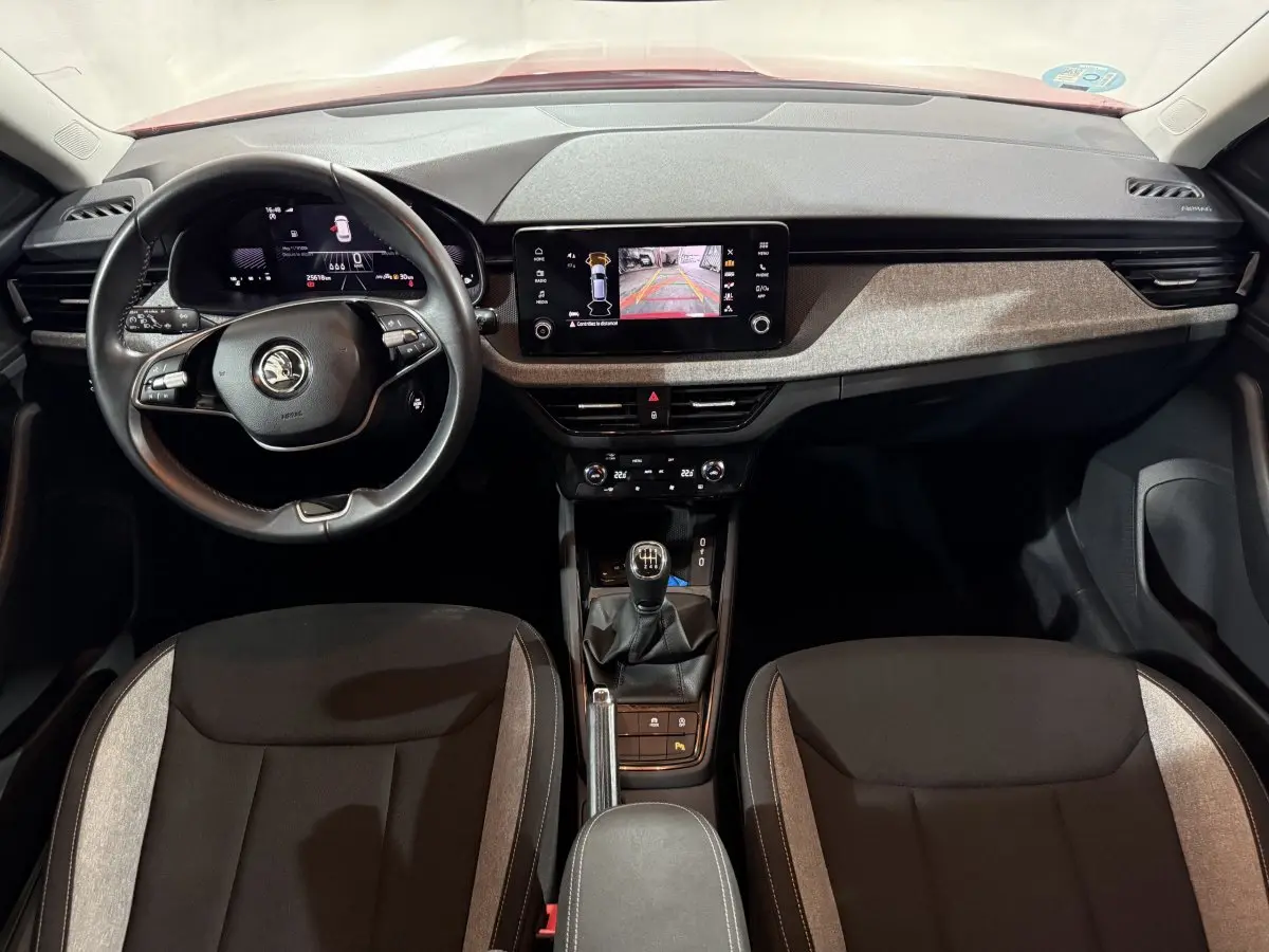 Vue intérieure frontale du tableau de bord et volant cuir noir du Skoda Kamiq 2024 avec écran tactile et levier de vitesses manuel.