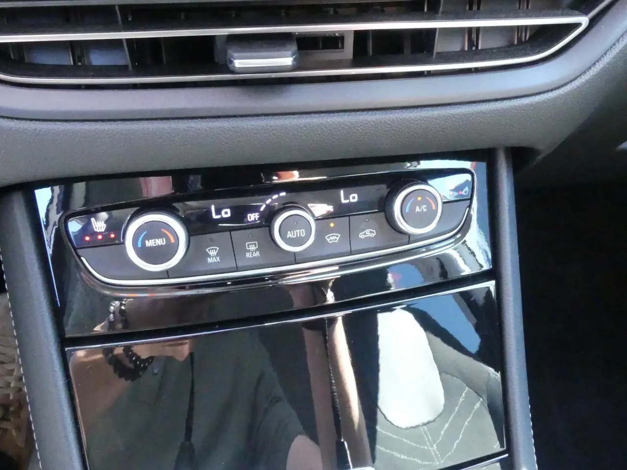 Vue rapprochée de la console centrale noire brillante avec commandes de climatisation et chauffage sur Opel Grandland blanc.