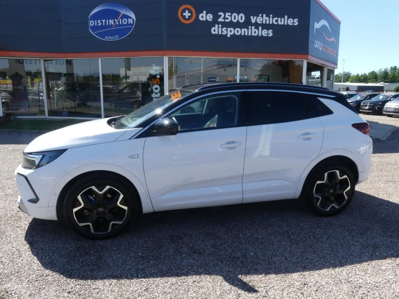 Opel Grandland blanc métallisé vu de profil côté gauche avec toit noir brillant et jantes alliage noires.