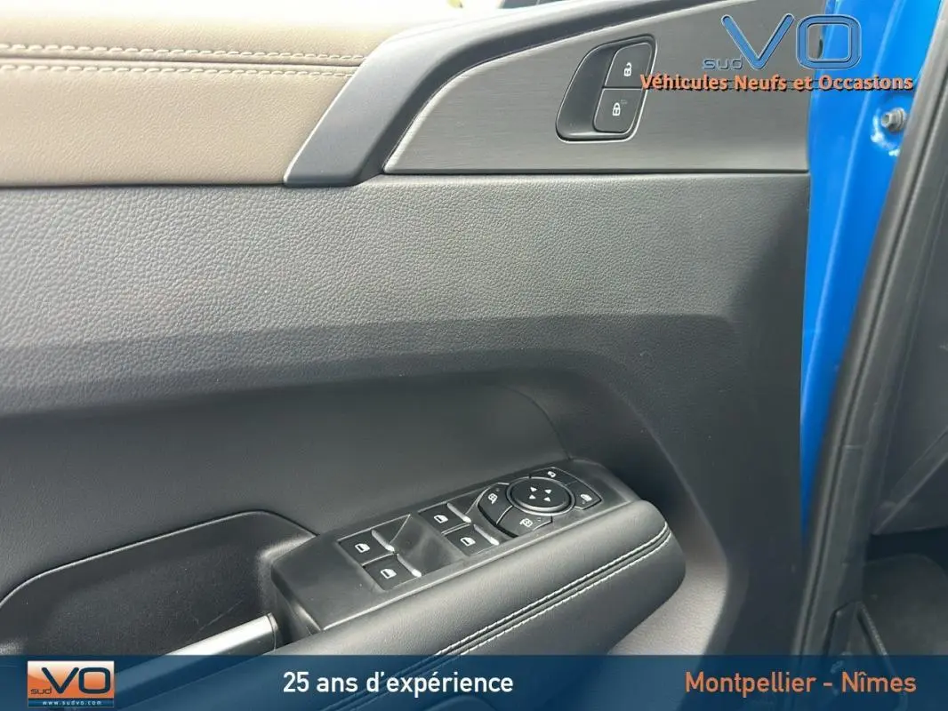 Gros plan sur la porte côté conducteur du Volkswagen Amarok bleu, avec commandes de vitres et serrure visibles.