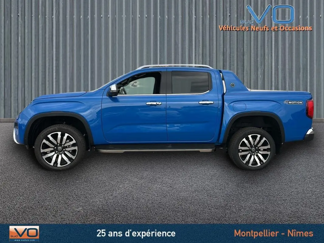 Vue de profil côté gauche du pick-up Volkswagen Amarok Simple Cabine bleu avec jantes alliage 21 pouces et marchepieds visibles.