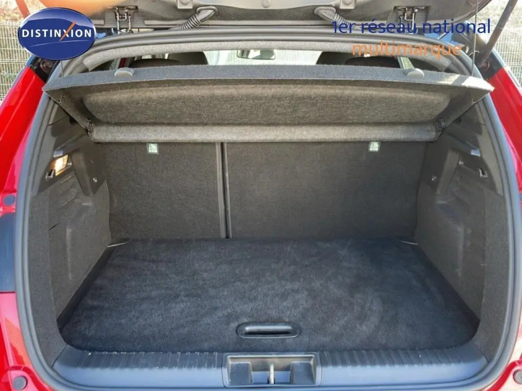 Coffre ouvert vu de l'arrière d'un Renault Captur rouge 2025, montrant un espace de chargement vide et propre.