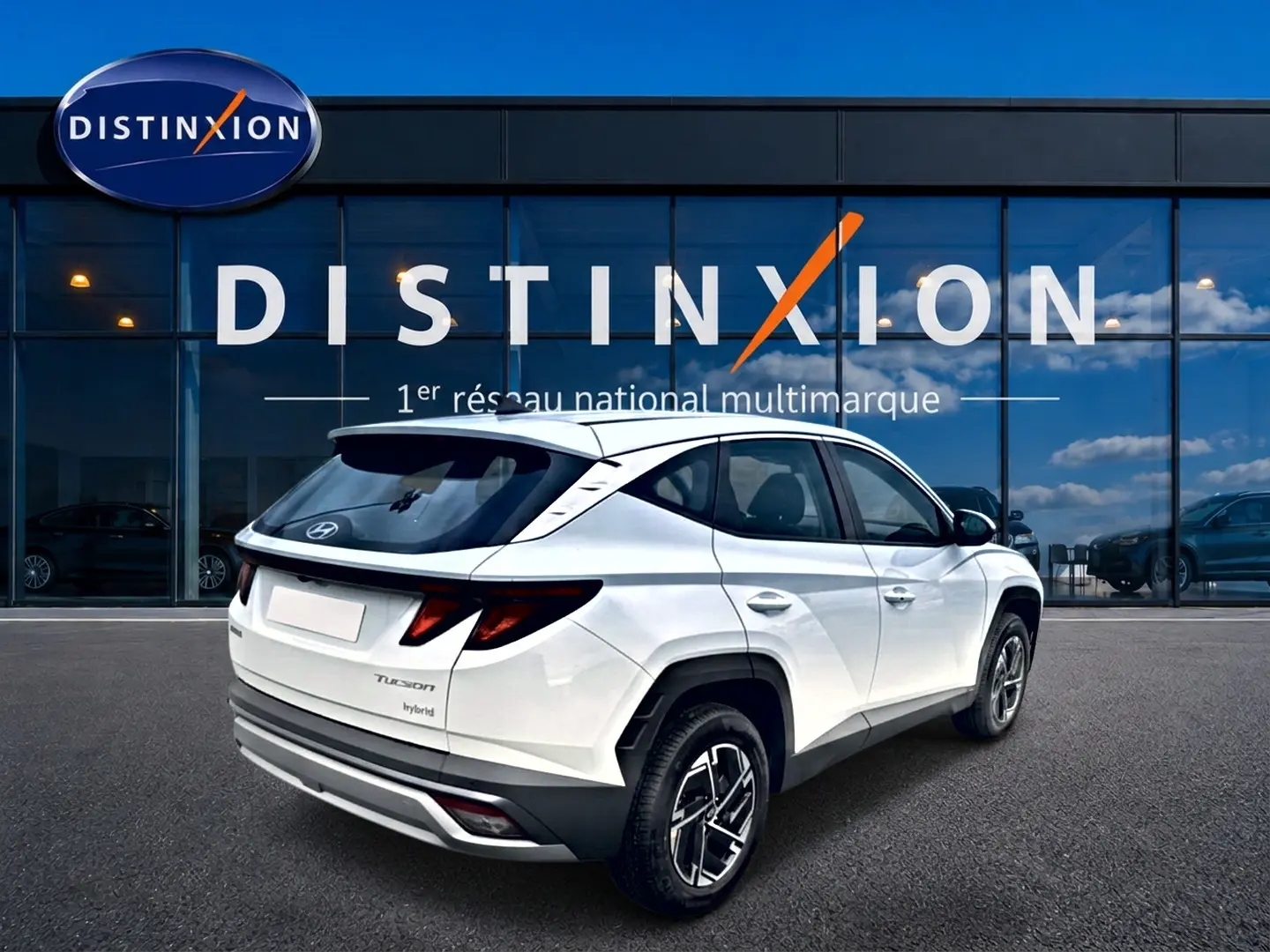 Vue 3/4 arrière droite du Hyundai Tucson blanc hybride 2026 devant une vitrine Distinxion.