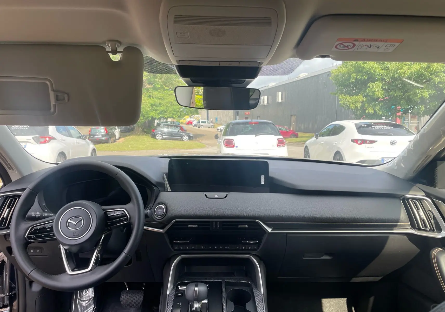 Vue intérieure avant du Mazda CX-60 2024 en finition Homura, tableau de bord noir avec écran central et volant multifonction.