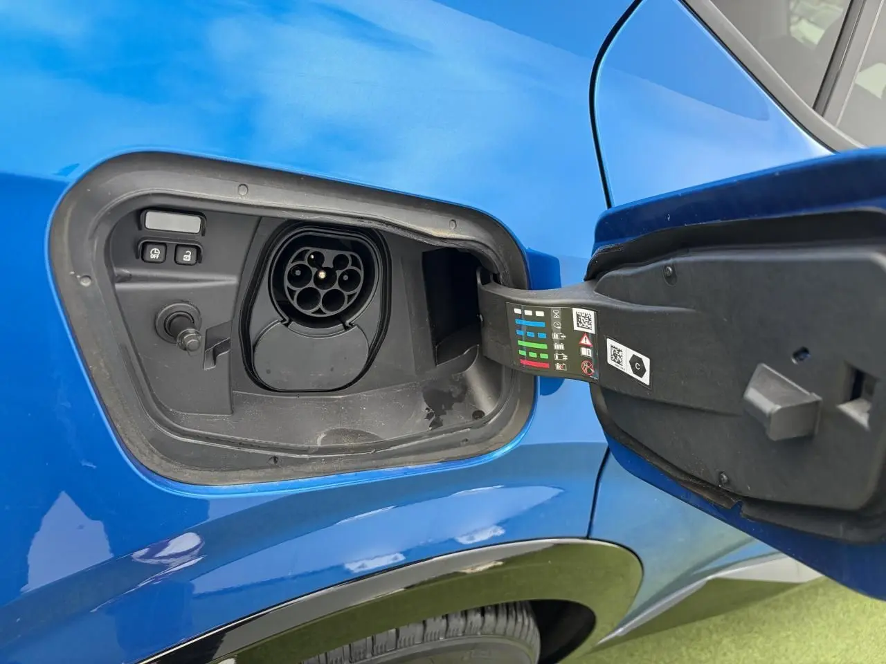 Prise de recharge ouverte côté gauche sur Renault Rafale Summit Blue, montrant le port de charge hybride rechargeable.