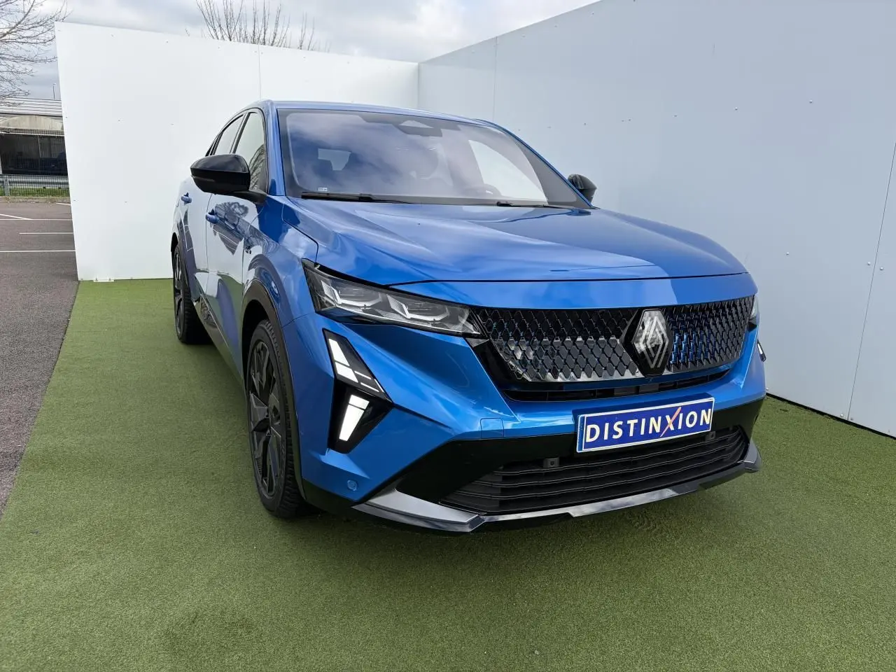 Renault Rafale 2025 bleu Summit, vue 3/4 avant avec calandre noire et feux LED distinctifs.