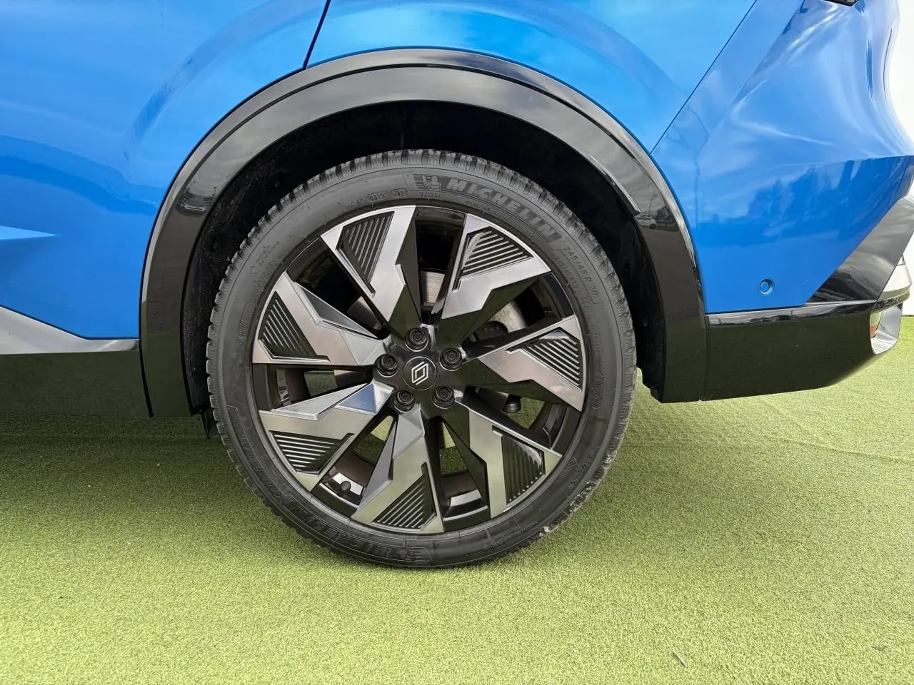 Gros plan sur la roue arrière droite du Renault Rafale Summit Blue avec jante alliage noire et grise au design géométrique.